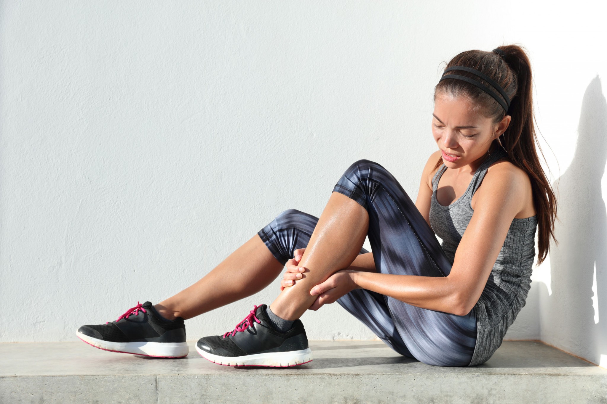 sport woman runner hurting holding painful sprained ankle in pain
